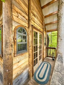 a porch of a wooden cabin with a large window at Off-Grid Treehouse White Mountain National Forest in North Lovell +20 photos