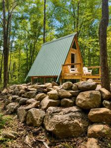 a cabin in the woods behind a pile of rocks at White Mountains A-Frame Off-Grid Stars Firepit in North Lovell