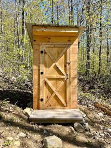 a wooden outhouse with a door in the woods at White Mountains A-Frame Off-Grid Stars Firepit in North Lovell