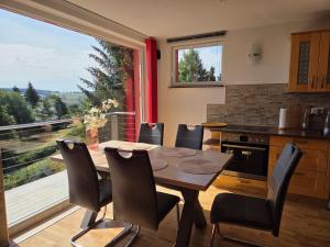 a kitchen with a table and chairs and a large window at Ski- und Wanderurlaub im Wald Ferienhaus Adlerblick in Schnett