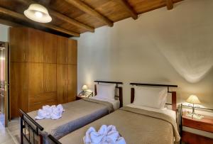 two beds in a bedroom with wooden ceilings at Rodoula apts By Comfortbnb in Roússa Ekklisía
