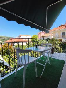 a table and a chair under an umbrella on a balcony at Parga Heritage in Parga