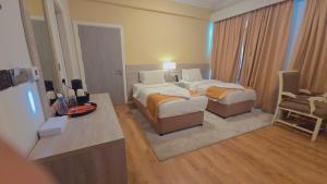 a hotel room with two beds and a desk at Mirador Hotel in Manama