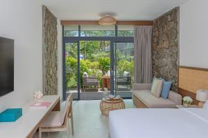 a hotel room with a king sized bed and a living room at Avani Plus Barbarons Seychelles Resort in Grand'Anse +70 photos