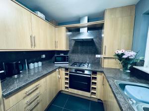 a kitchen with wooden cabinets and a stove top oven at Queens Townhouse - 4 Bedrooms - Sleeps 9 in Whitehaven +20 photos