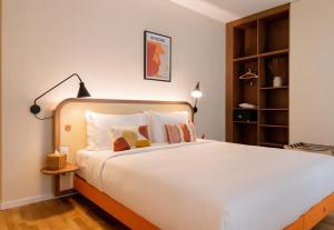 ein Schlafzimmer mit einem großen weißen Bett und Kissen in der Unterkunft HOOD Hotel in Genf