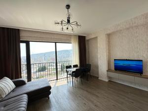 a living room with a couch and a television and a table at GM Apartment in Tbilisi City