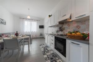 a kitchen with white cabinets and a table with a basket of fruit at Blu Mare Apartments in San Vito lo Capo