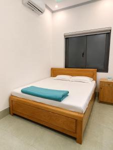 a bedroom with a wooden bed with a window at Khách sạn Đạt Tiến Quân in Ấp Bình Hưng