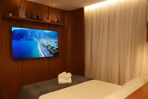 a bedroom with a tv on a wall with a bed at Tiwa Studio Requinte Amazônico Adrianópolis in Manaus