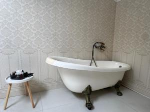 a white bath tub in a bathroom with wallpaper at Dare apartments 1 in Giurgiu