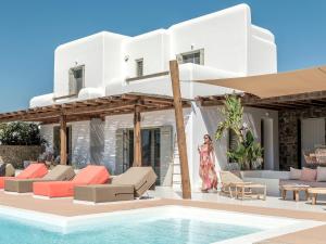 a villa with a swimming pool and a woman walking towards it at Villa Yasemin - Mykonos Paradise - Views - Pool - Large Garden in Kalafatis