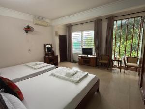 a bedroom with two beds and a desk with a television at Khách sạn Hùng Thắng in Vĩnh Lộc