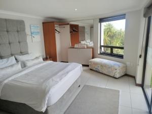 a large white bedroom with a large bed and a window at Sunset Cottage in Langebaan