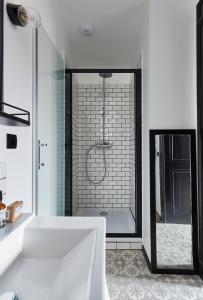 La salle de bains blanche est pourvue d'une baignoire et d'une douche. dans l'établissement Le Boutik Hotel, à Annecy