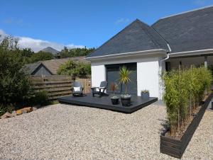 a patio with a bench and a chair in a yard at Wee Catriona in Brodick