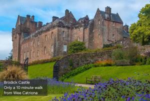 an old castle with flowers in front of it at Wee Catriona in Brodick +28 photos