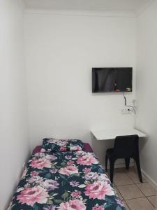 a bedroom with a bed and a desk and a tv at LRN Brackenfell Homestay in Cape Town