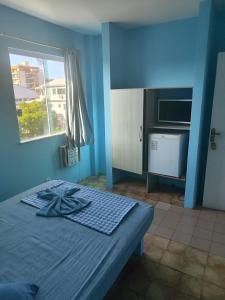 a blue room with a bed and a window at Hotel Nanuque in Cabo Frio