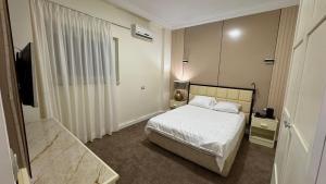 a bedroom with a white bed and a television at Rosaio in El Alamein