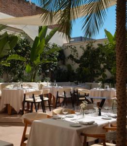 a restaurant with white tables and chairs and palm trees at La Fonda Heritage Hotel Luxury, Relais & Châteaux in Marbella