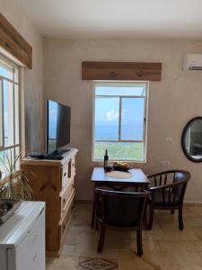 a kitchen with a table and a television and a table and chairs at Benichuta in Mitzpe Hila