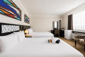 a hotel room with two beds and a couch at ONOMO Hotel Cape Town – Inn On The Square in Cape Town