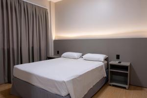 a bedroom with a large white bed with a night stand at Village Iguassu Hotel in Foz do Iguaçu +37 photos