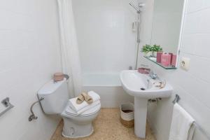 a white bathroom with a toilet and a sink at Hotel Bulevard in Platja d'Aro +17 photos