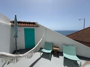 two chairs and a hammock on a balcony at Aqua Sea House in Madalena do Mar
