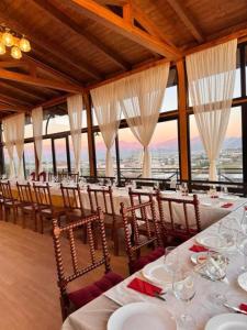 a dining room with white tables and chairs and windows at Vila Shehi Guesthouse and Winery in Tirana
