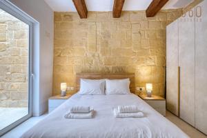 a bedroom with a large white bed with two pillows at Luqa Stone Maisonette Apartments Near Airport in Luqa
