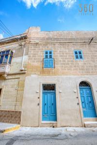 a brick building with blue doors and windows at Luqa Stone Maisonette Apartments Near Airport in Luqa