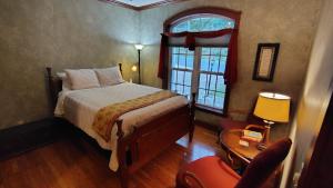 a bedroom with a bed and a window and a chair at North River Inn in Bridgewater