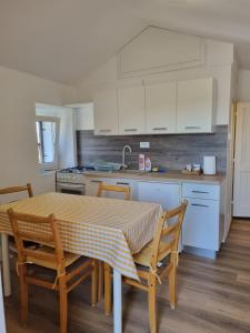 a kitchen with a table and chairs and white cabinets at Macmalić in Zbičina