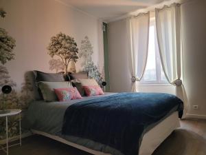 a bedroom with a bed with a blue blanket and a window at L'Annexe de Steph in Loulans-Verchamp