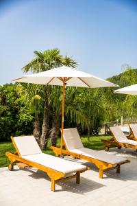 a row of lounge chairs and an umbrella at Masseria Marotta in Santa Paolina