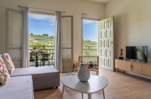 a living room with a couch and a table and a tv at Flower in Skiathos