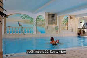 two people in a swimming pool at a hotel at die Harmonie in Nauders