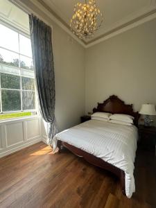 a bedroom with a bed and a chandelier and a window at Uppercourt Manor in Freshford +1 photo