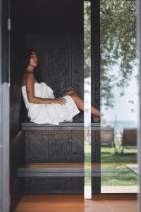 a woman sitting on a bench in a window at Hotel Baia Azzurra - Lake Front in Nago-Torbole +32 photos