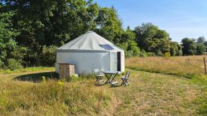 a tent with two chairs and a table in a field at Yourtes insolites in Querrien