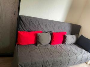 a gray couch with four red pillows on it at FeWo Möwennest in Warnemünde