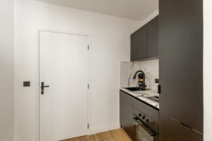 a kitchen with white cabinets and a white door at L'Aube des Alpes Hyper Centre Élégance et Confort in Thonon-les-Bains