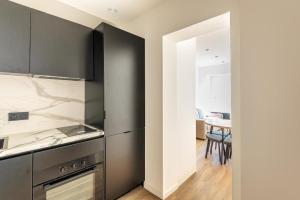 a kitchen with black and white appliances and a table at L'Aube des Alpes Hyper Centre Élégance et Confort in Thonon-les-Bains