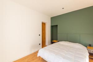 a bedroom with a white bed and a green wall at L'Aube des Alpes Hyper Centre Élégance et Confort in Thonon-les-Bains