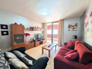 a living room with a red couch and a tv at CHC - Olivia Sunset II in Puerto de Santiago
