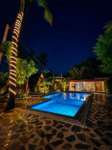 a swimming pool next to a palm tree at night at Sheen Coast Beach Cabana in Nilaveli +24 photos