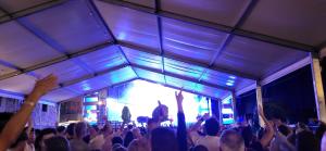 a crowd of people raising their hands in front of a stage at El Juacu in Llanes