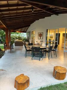 a patio with a table and chairs and wooden logs at Guarajuba com 5 suítes, piscina e espaço gourmet in Camacari